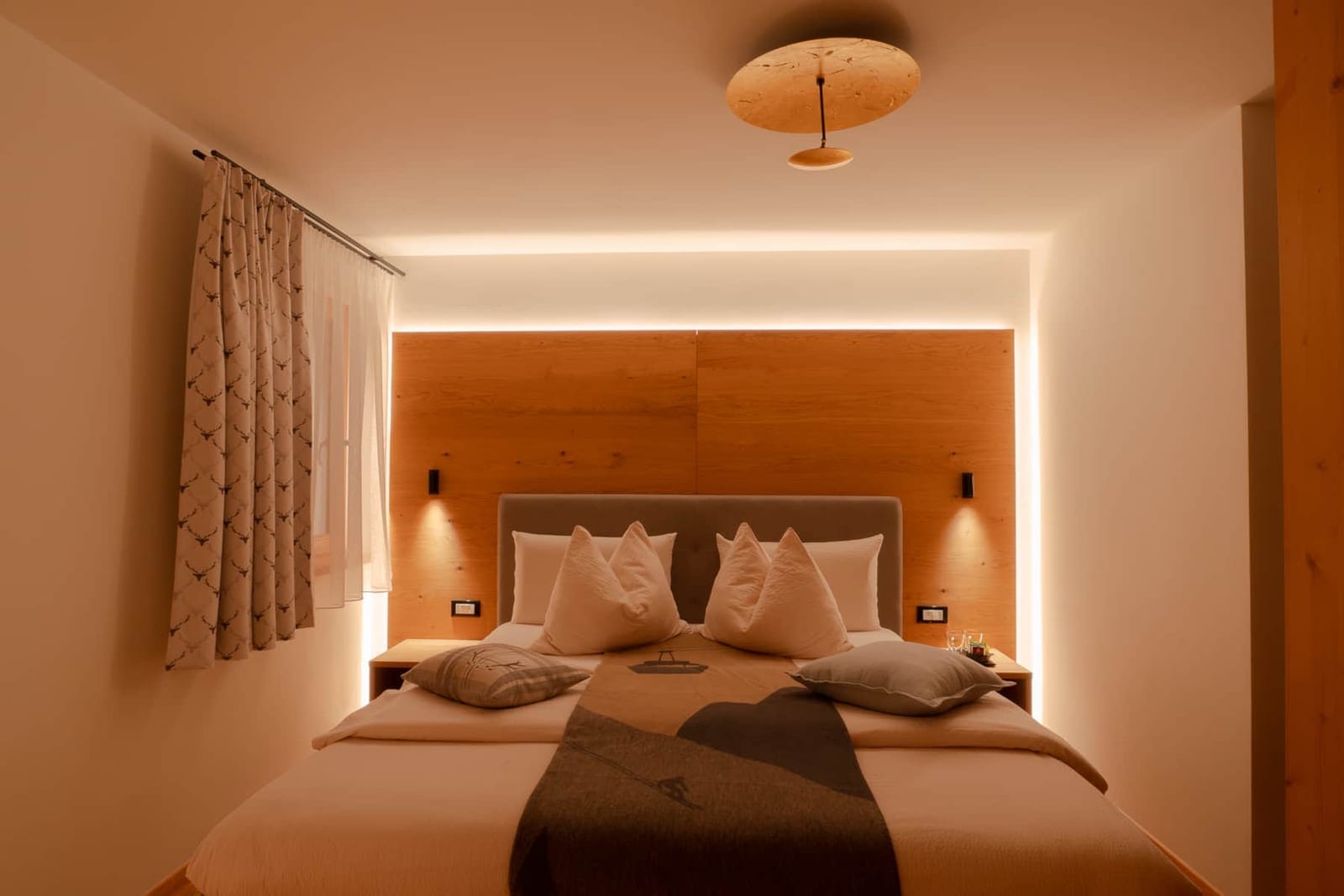 Ardesia: letto king size con testata in legno e luce soffusa.