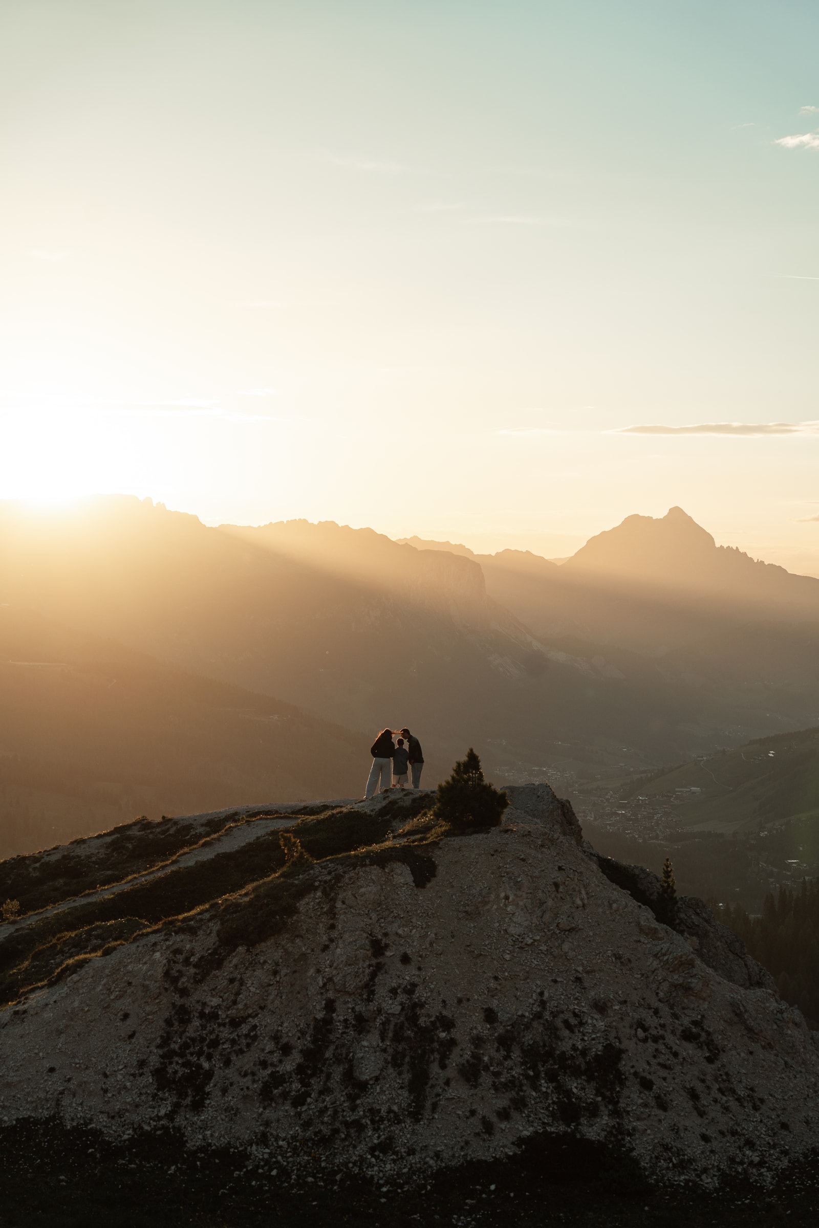 Silhouetten auf einem Bergrücken, mit Sonnenstrahlen über dem Tal.